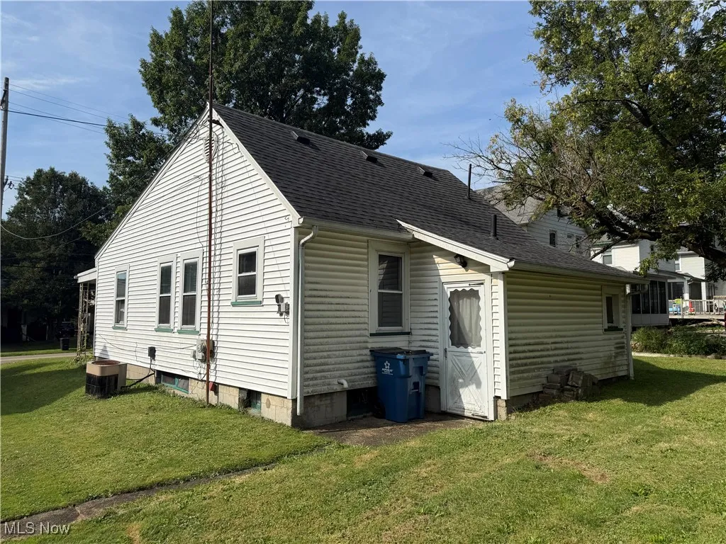 Rear view of property featuring a yard and roof with shingles