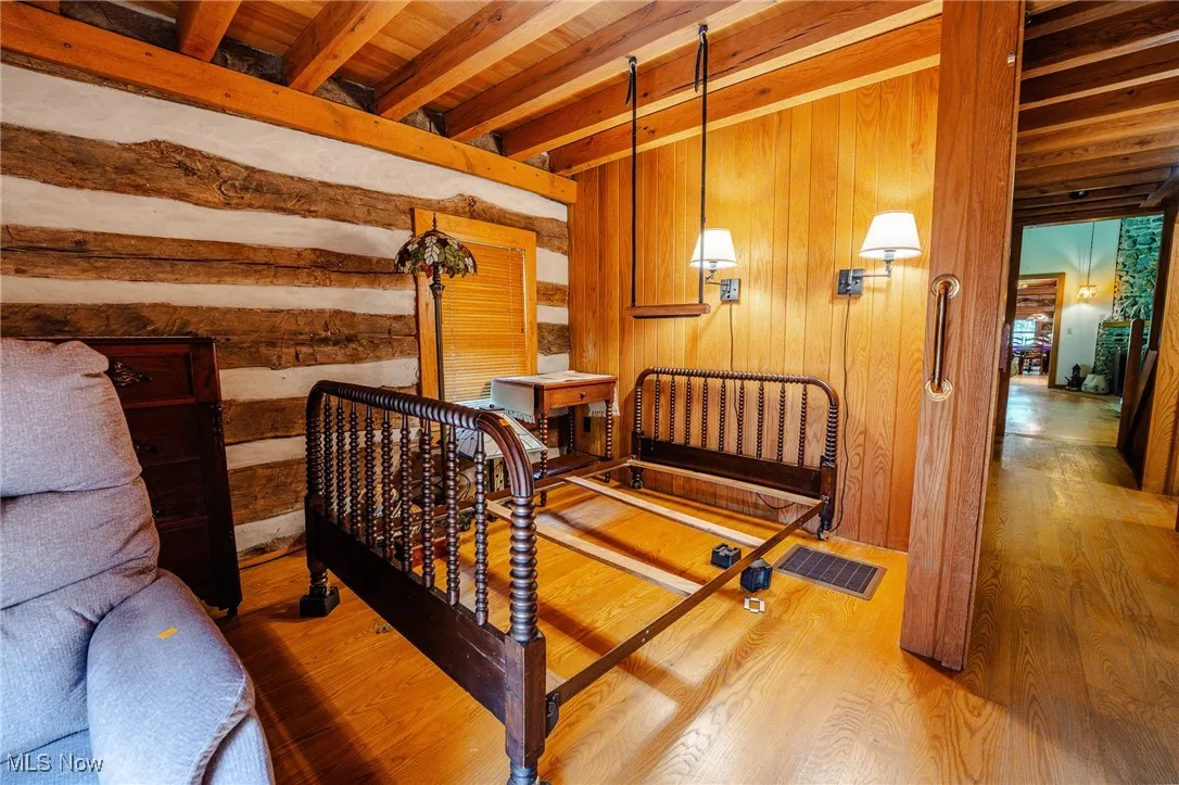 Bedroom with wood walls, wood finished floors, and a wooden ceiling with exposed beams
