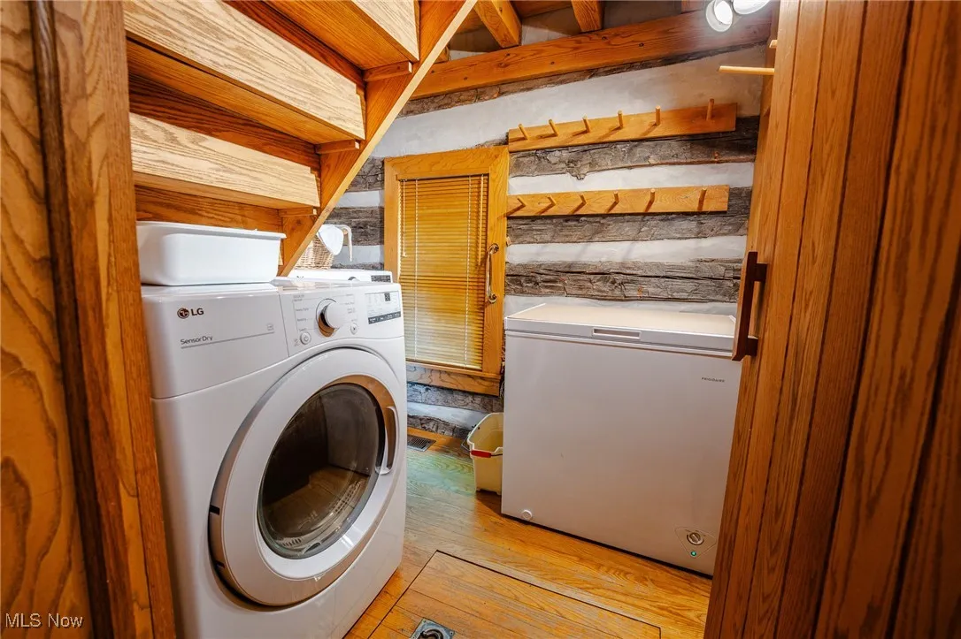 Washroom with separate washer and dryer and light wood-type flooring