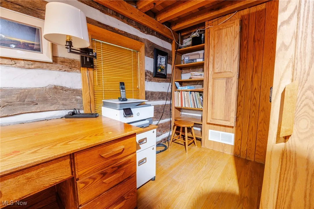 Office area featuring light wood-style floors and beamed ceiling