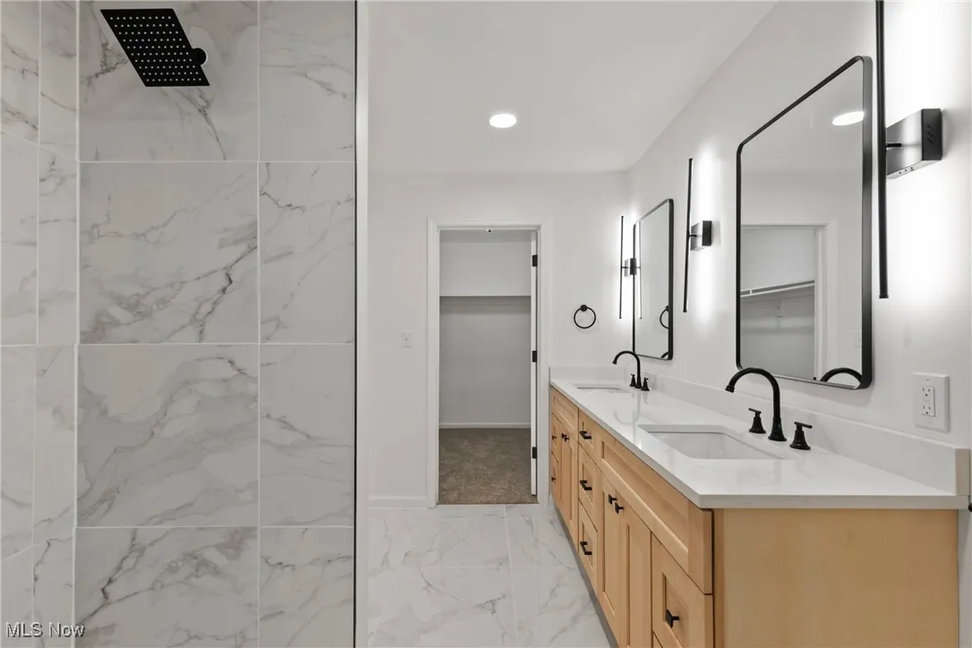 Full bathroom with double vanity, recessed lighting, light marble finish floors, a marble finish shower, and a walk in closet
