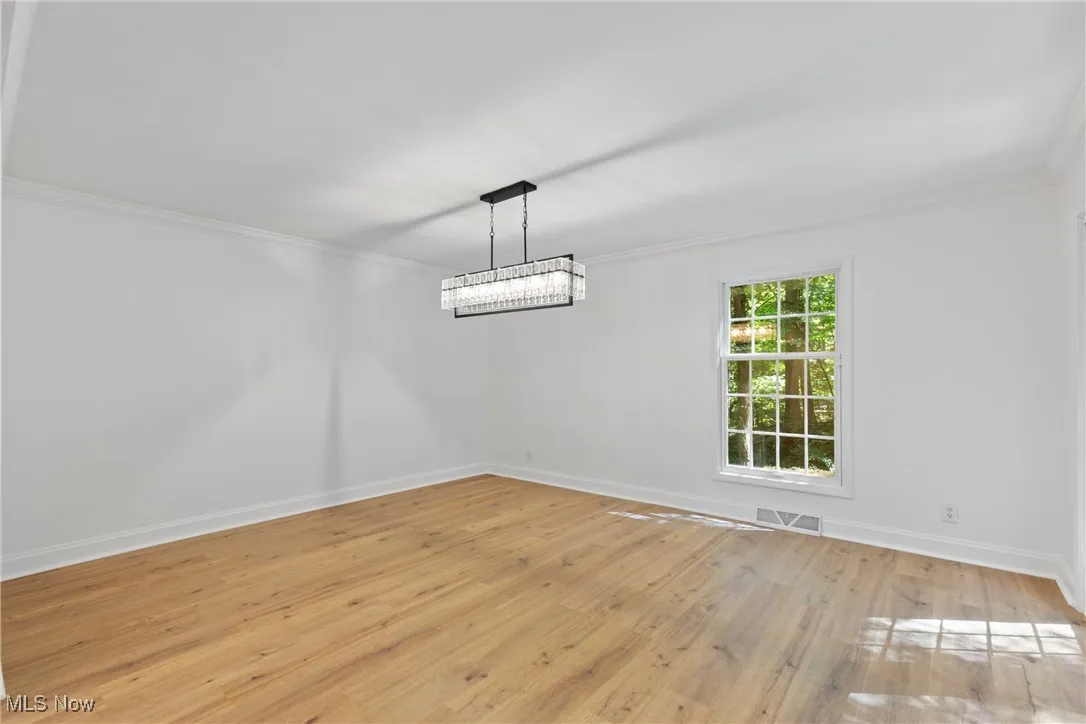 Unfurnished dining area with light wood-type flooring and crown molding