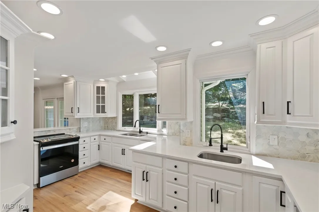 Kitchen featuring stainless steel range with electric cooktop, ornamental molding, light wood-style flooring, recessed lighting, and tasteful backsplash