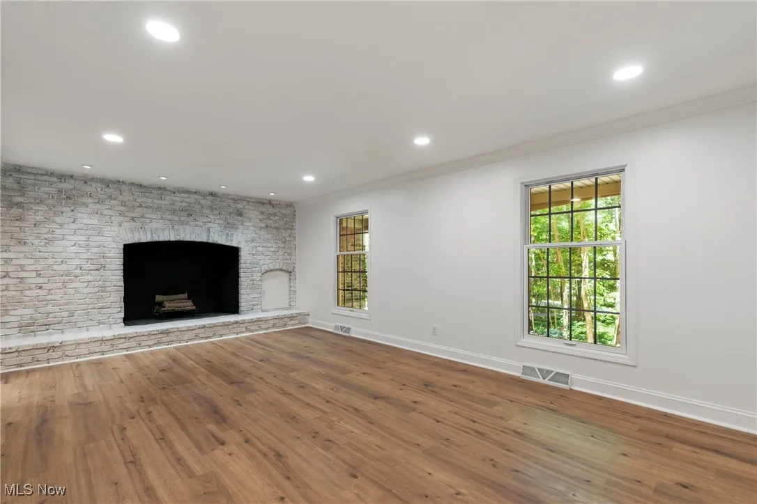 Unfurnished living room featuring hardwood / wood-style floors, ornamental molding, recessed lighting, and a fireplace