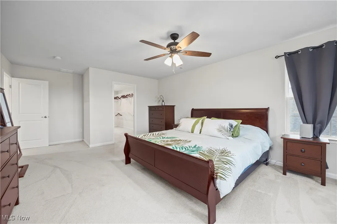 Bedroom with light colored carpet, a ceiling fan, and connected bathroom