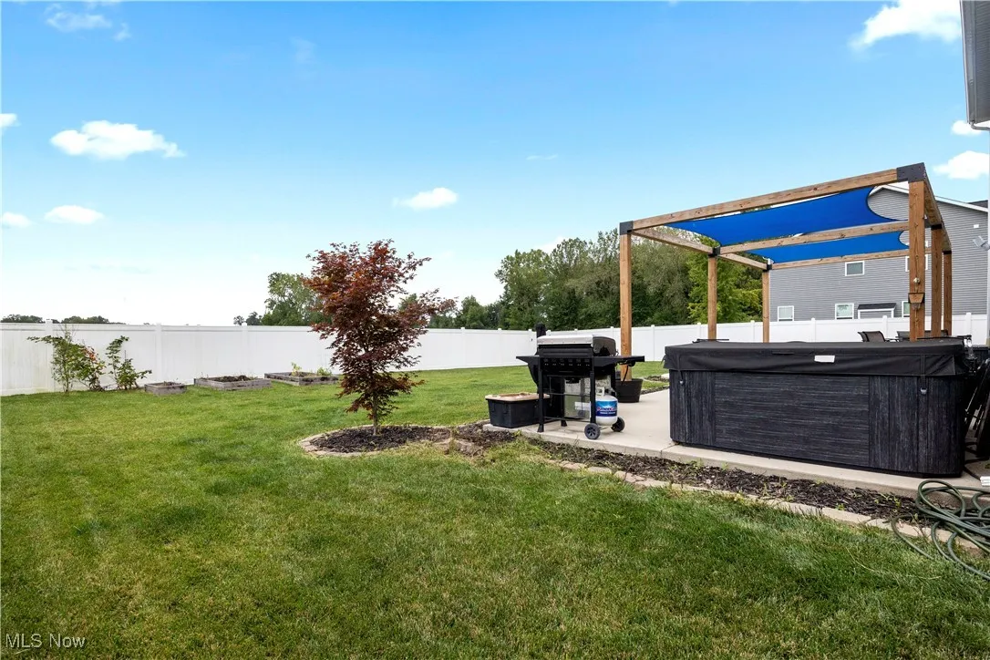 Fenced backyard featuring a patio area and a hot tub
