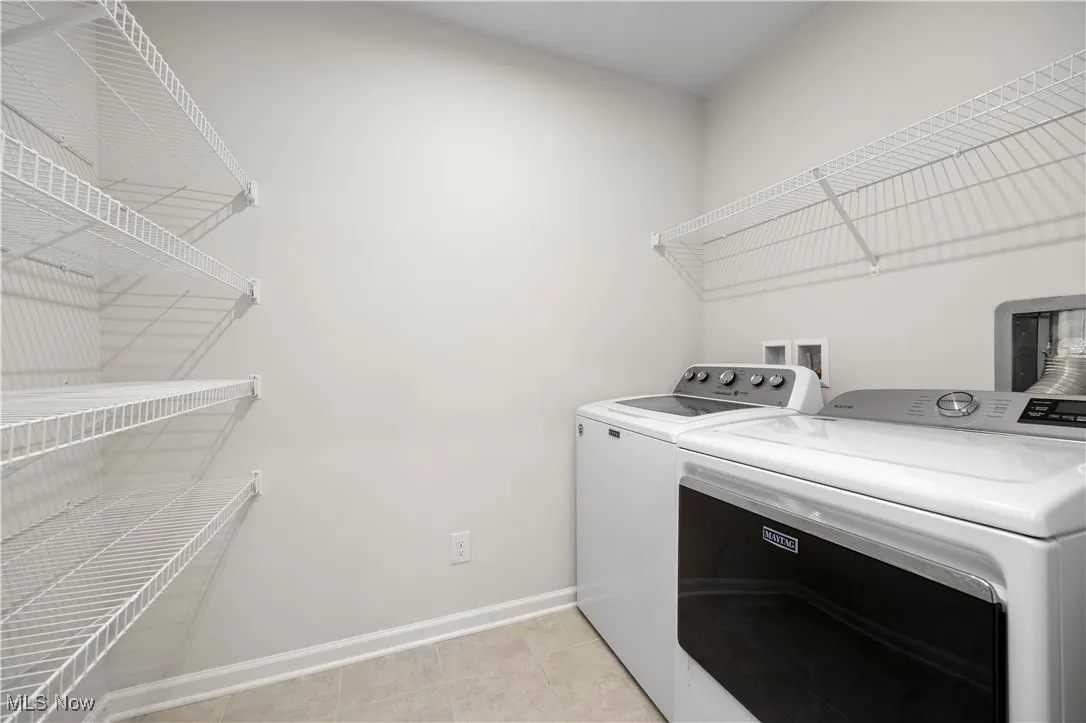 Washroom with light tile patterned floors and separate washer and dryer