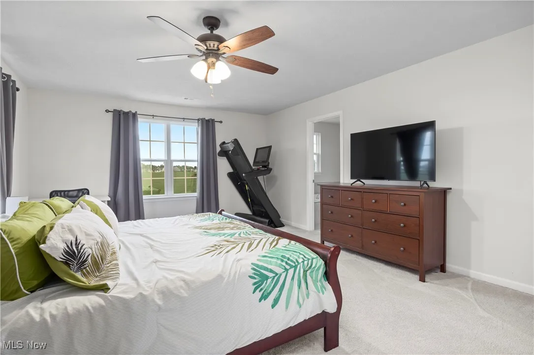 Bedroom featuring light colored carpet, a ceiling fan, and ensuite bathroom