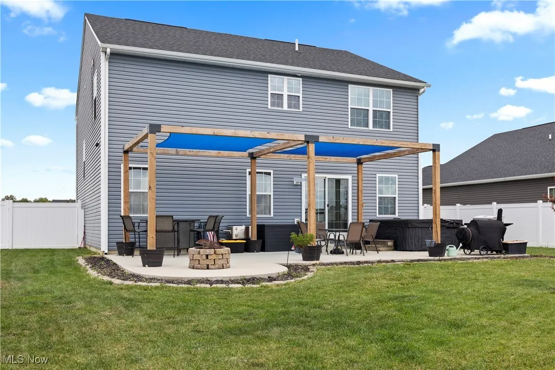 Back of property with a fenced backyard, an outdoor fire pit, a patio, and a pergola