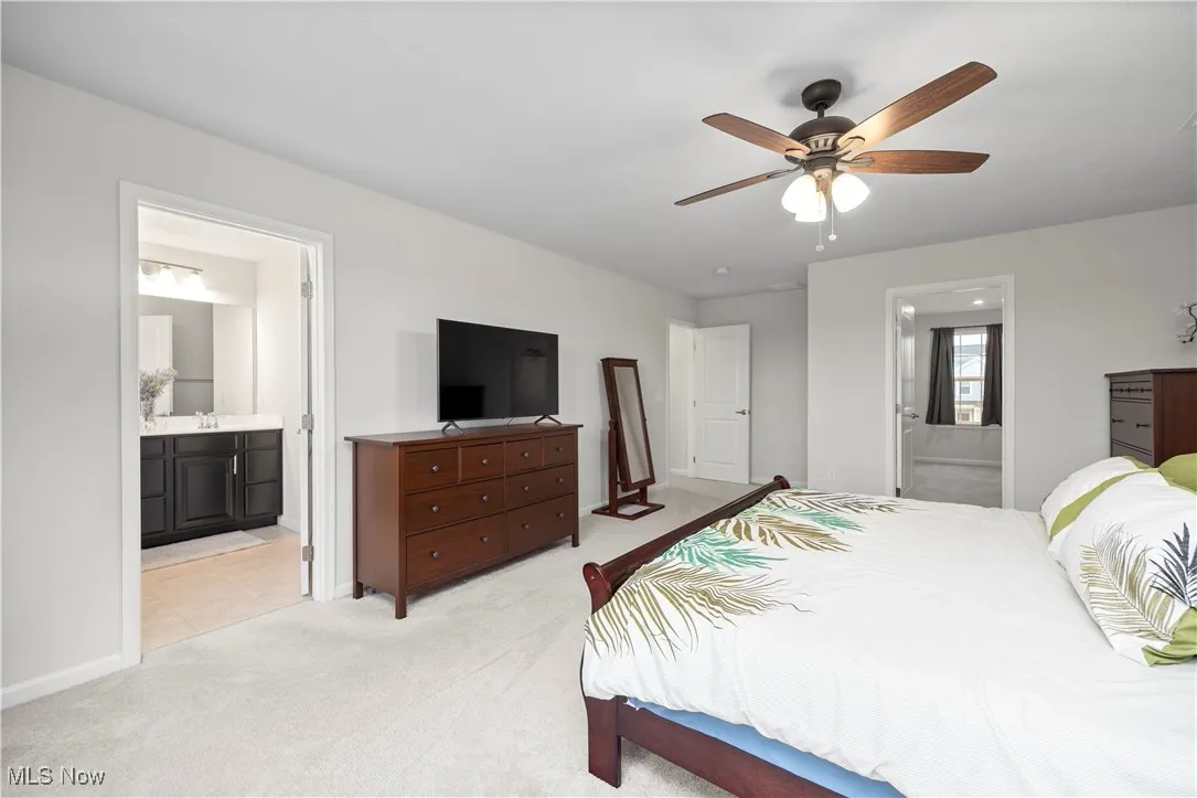 Bedroom featuring ensuite bathroom, light colored carpet, and a ceiling fan