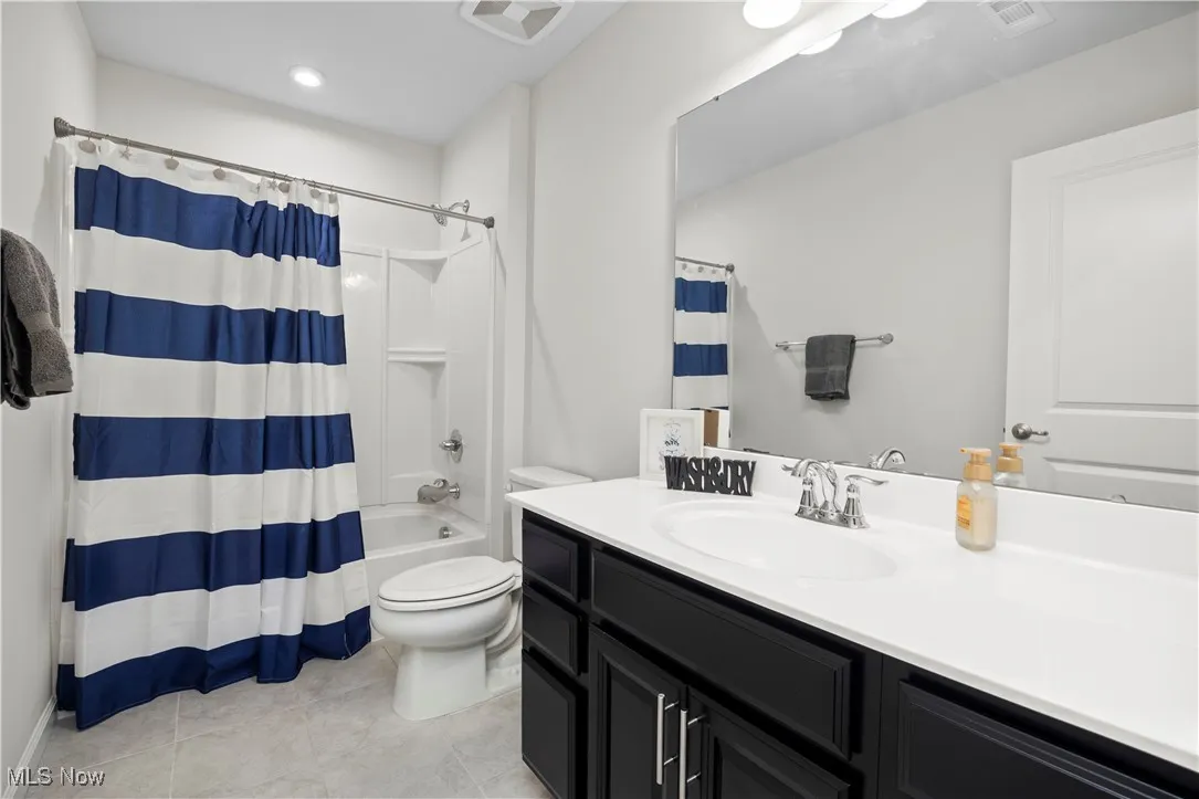 Bathroom featuring shower / bath combo, vanity, and light tile patterned floors