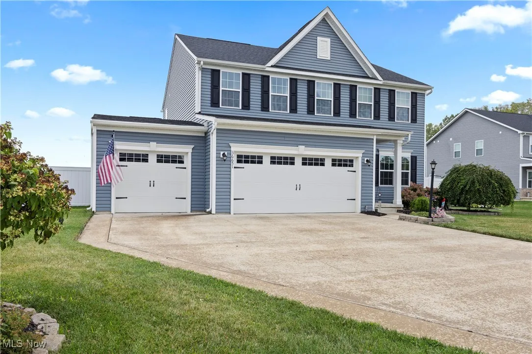 Traditional-style home featuring concrete driveway, a 3 car garage, and a front lawn
