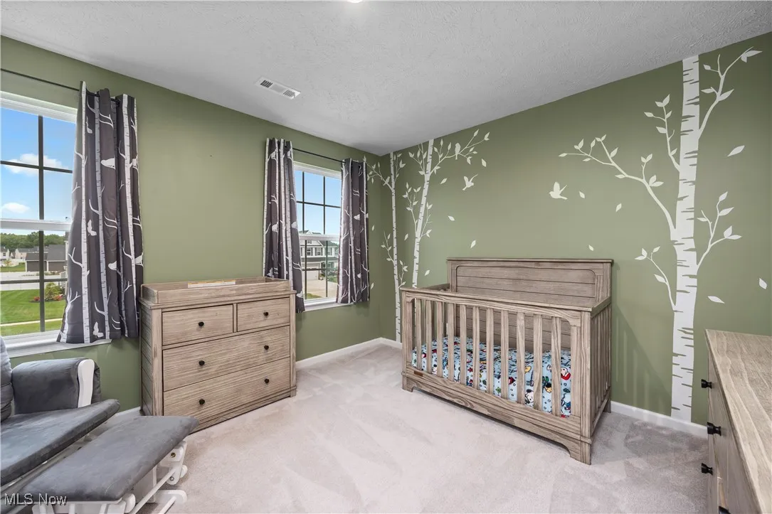 Bedroom with a crib, carpet floors, and a textured ceiling