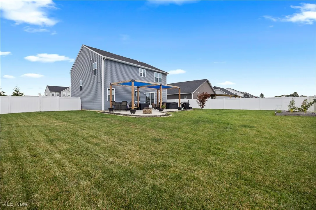 Rear view of property with a fenced backyard and a patio