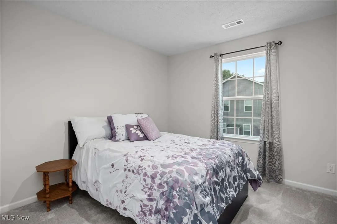 Bedroom featuring light colored carpet and a textured ceiling