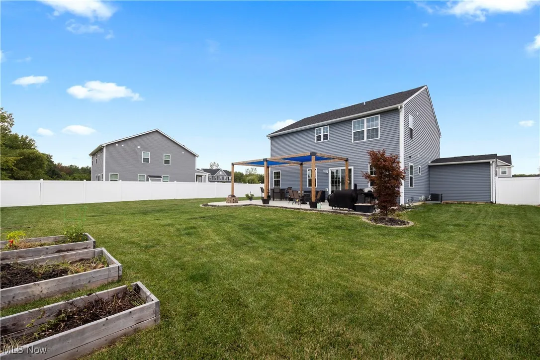 Back of property featuring a garden, a patio area, a fenced backyard, and a pergola