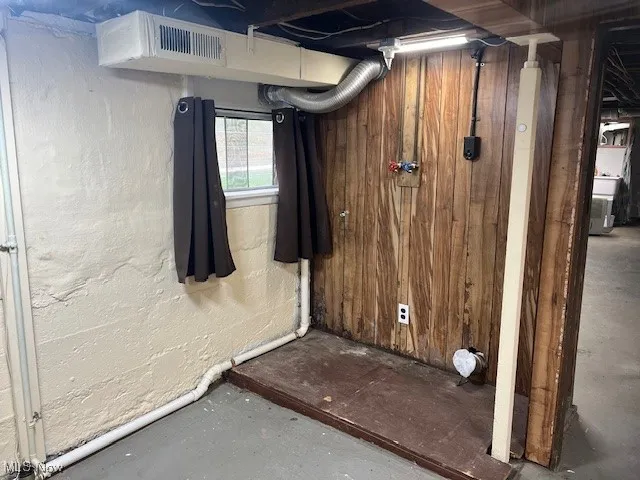 Bathroom with unfinished concrete flooring, a textured wall, and washer / dryer