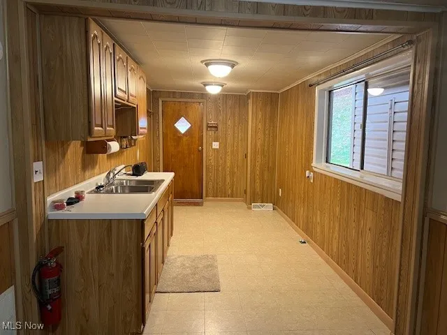 Kitchen with wooden walls, light countertops, light flooring, and brown cabinets