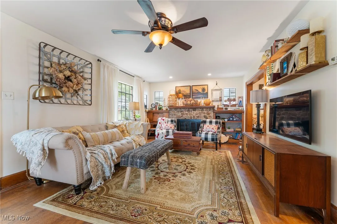 Living room with a fireplace, wood finished floors, and ceiling fan
