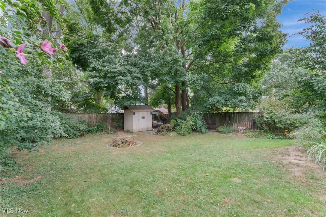 Fenced backyard featuring a storage unit and view of wooded area