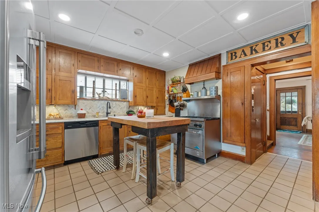 Kitchen featuring stainless steel appliances, healthy amount of natural light, brown cabinetry, tasteful backsplash, and recessed lighting