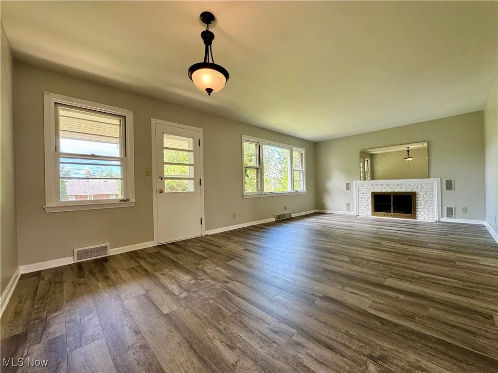 Unfurnished living room featuring a fireplace and dark wood finished floors
