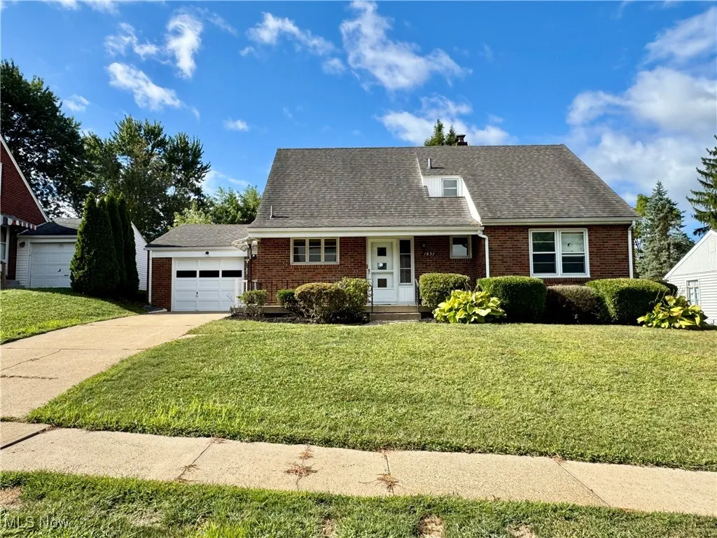 View of front of home with a porch, roof with shingles, a garage, and brick siding