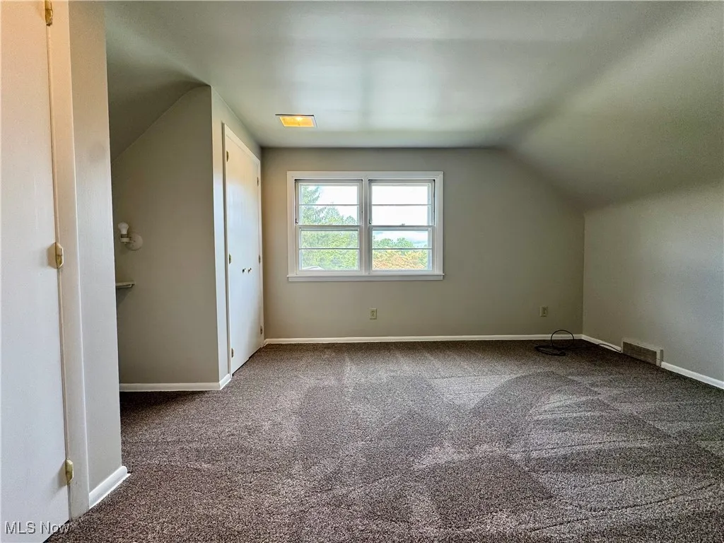 Additional living space with carpet flooring and vaulted ceiling