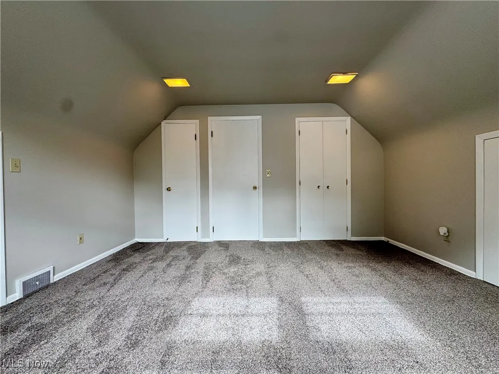 Additional living space featuring lofted ceiling and carpet