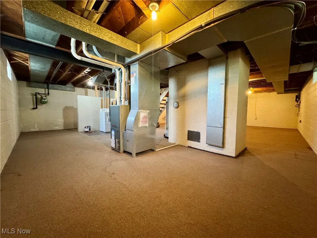 Unfinished basement with heating unit, washer / dryer, and water heater
