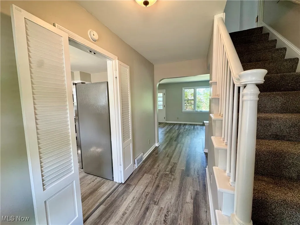 Hall with stairs, wood finished floors, and arched walkways