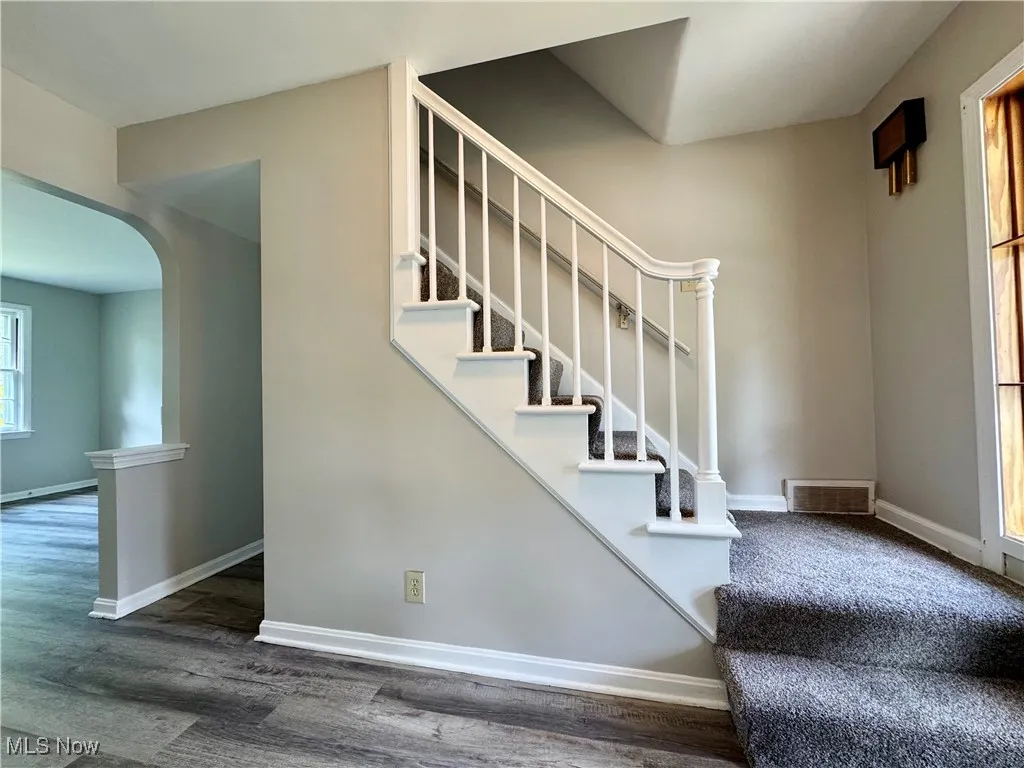 Stairs featuring arched walkways and wood finished floors