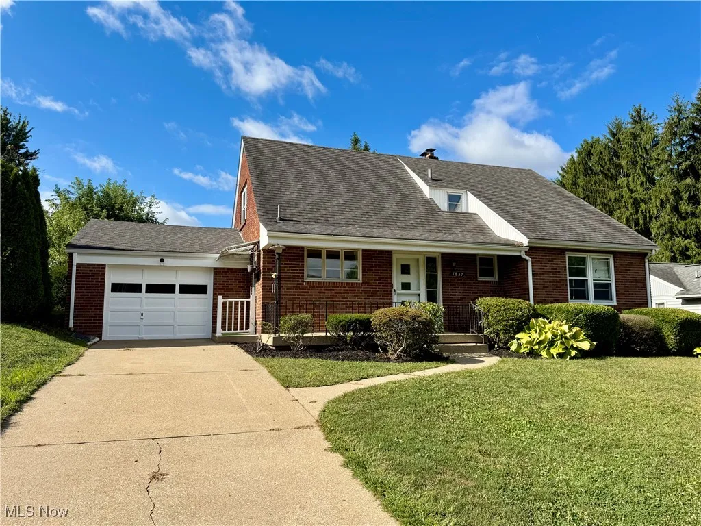View of front of home with a shingled roof, a garage, a front lawn, and a porch