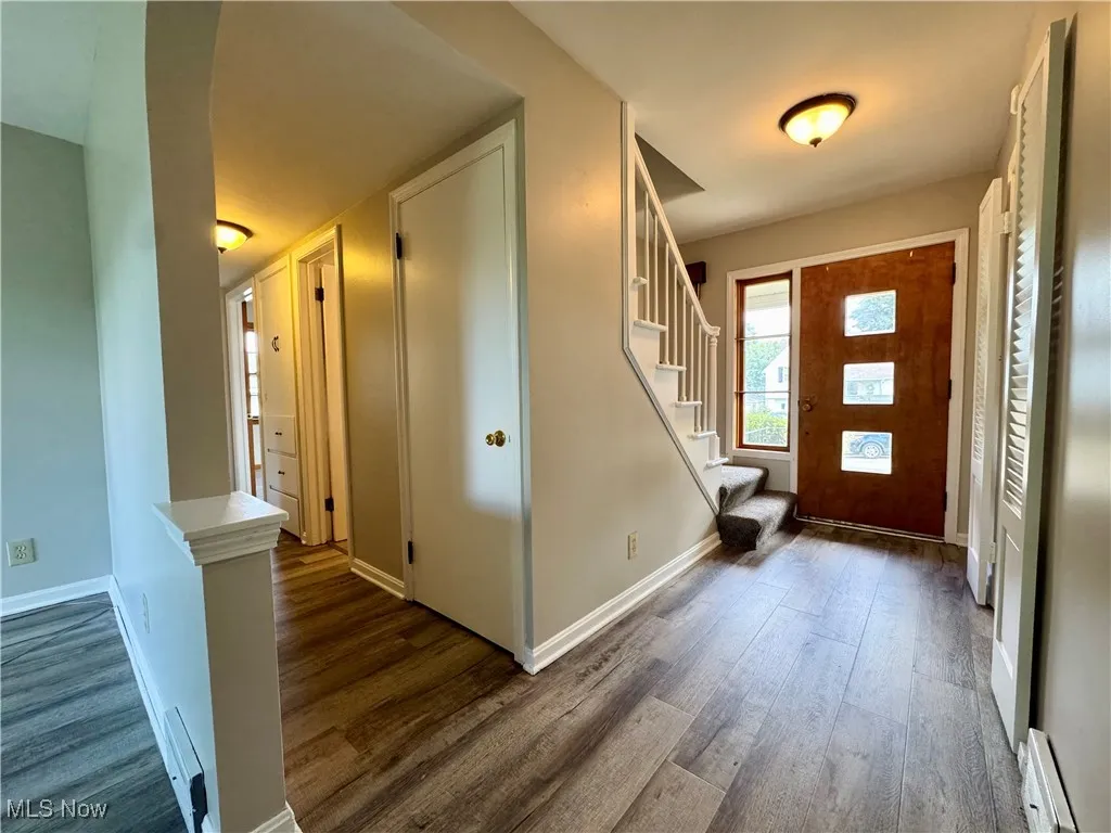 Entrance foyer featuring stairs, wood finished floors, and a baseboard heating unit