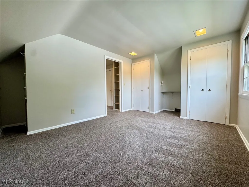 Unfurnished bedroom featuring carpet floors and two closets