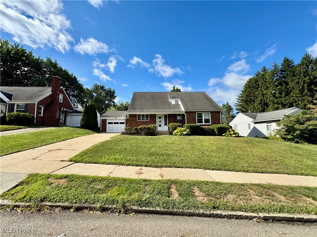 View of front of property featuring brick siding, concrete driveway, a garage, and a front yard