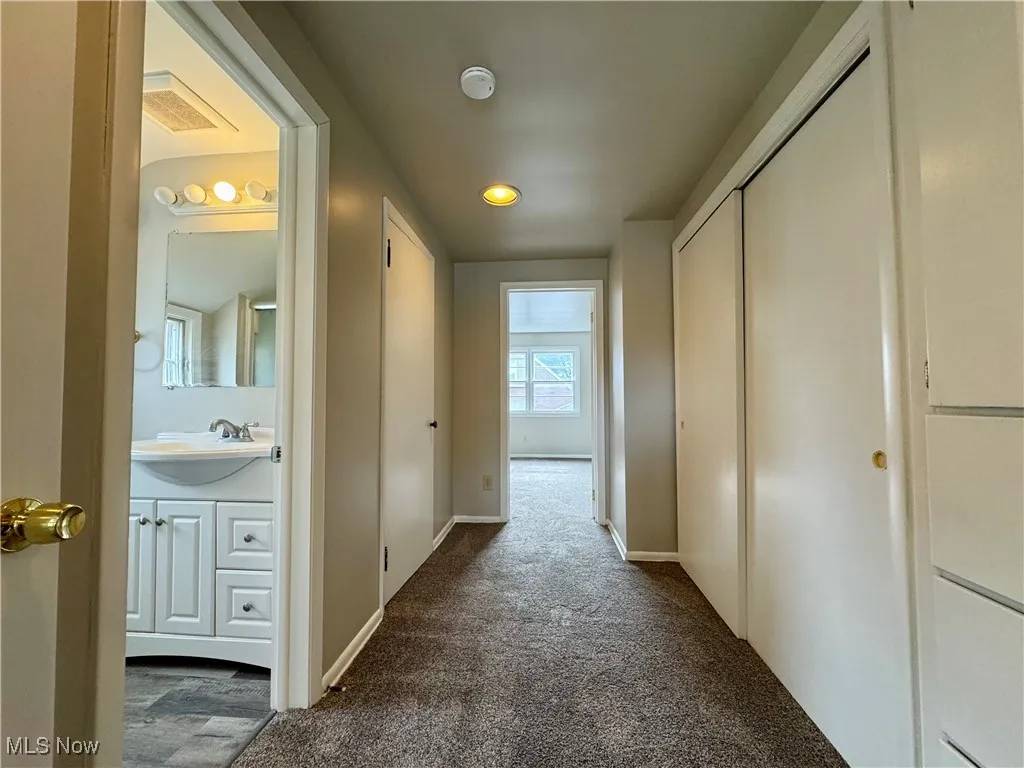Corridor featuring dark colored carpet and recessed lighting