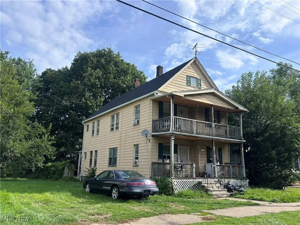 View of front of property with a porch, a chimney, and a front lawn