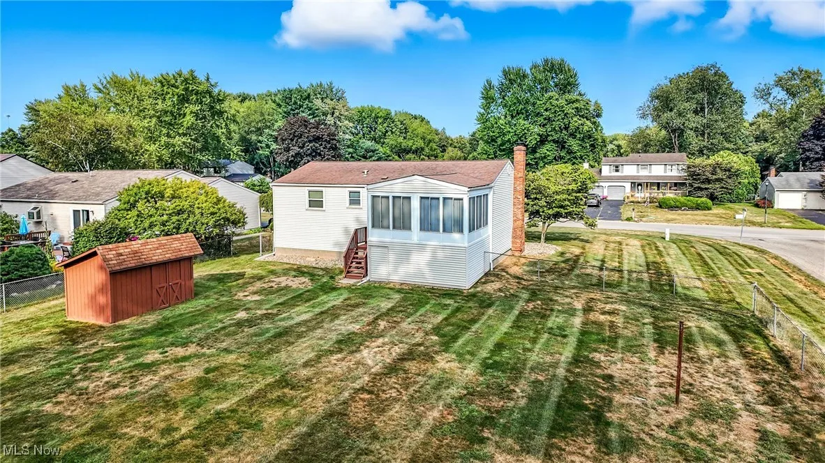 Back of house featuring a sunroom, a shed, a fenced backyard, and a chimney