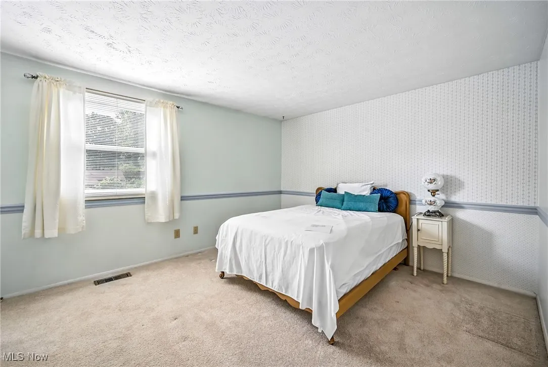Bedroom featuring carpet floors, a textured ceiling, and wallpapered walls