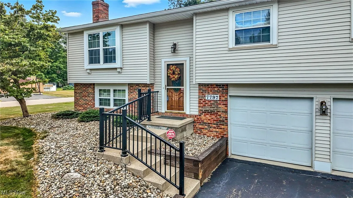 View of front facade featuring brick siding, a chimney, asphalt driveway, and a garage