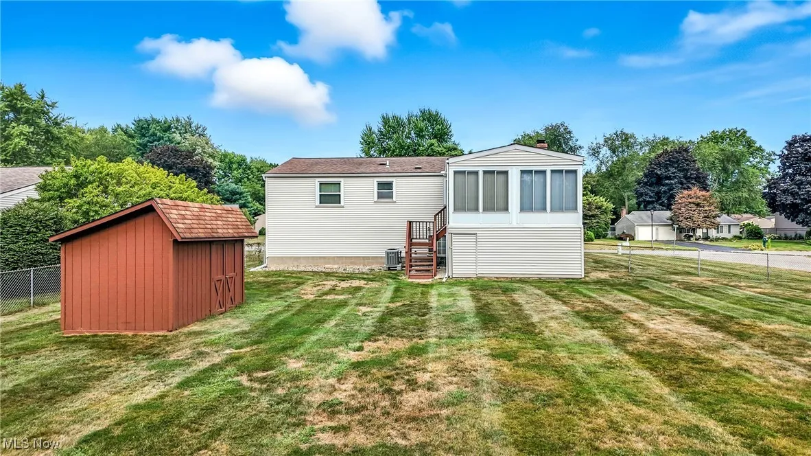 Back of property with a sunroom and a storage unit