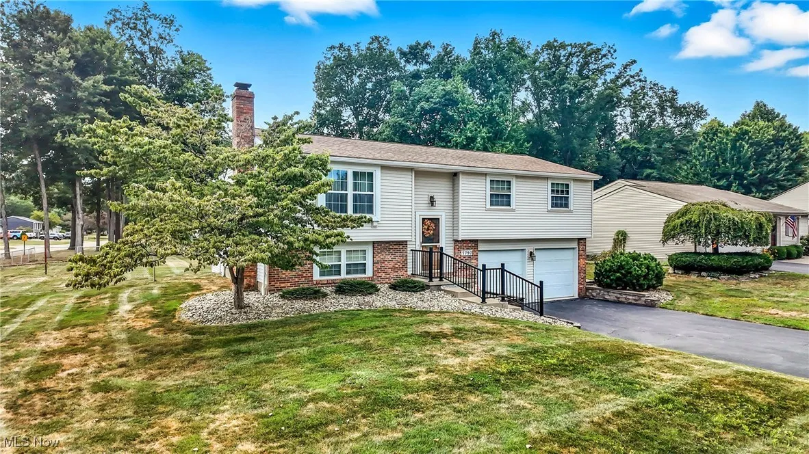 Split foyer home with brick siding, a chimney, a front yard, and asphalt driveway