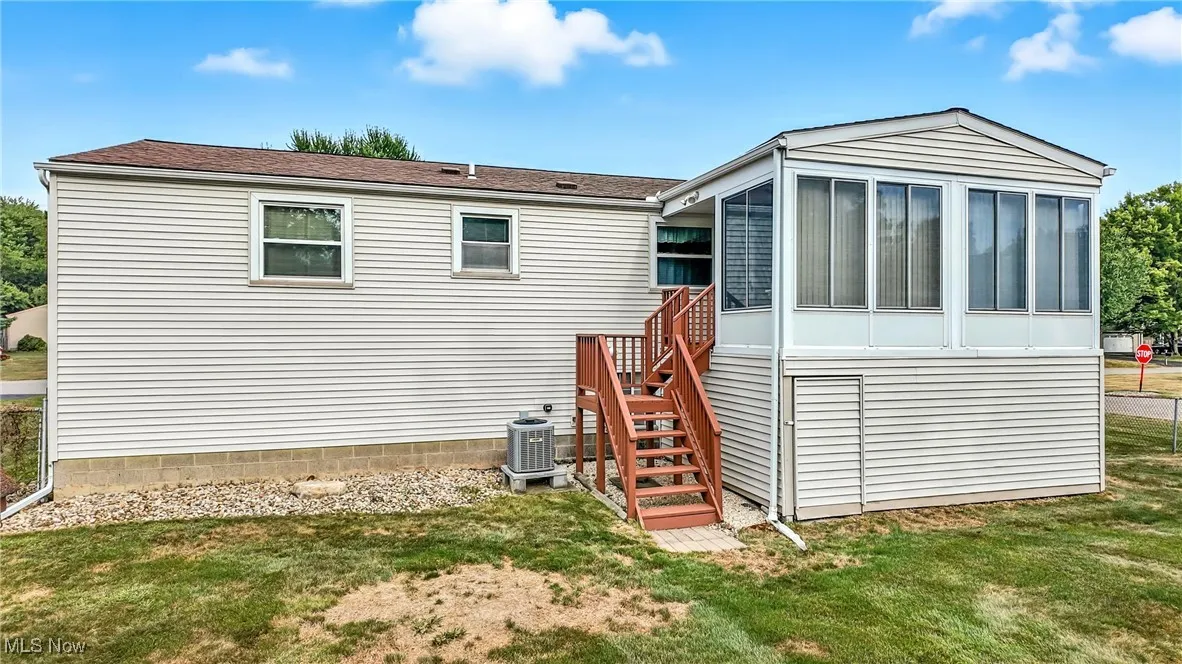 Rear view of property featuring a sunroom, stairway, and a yard