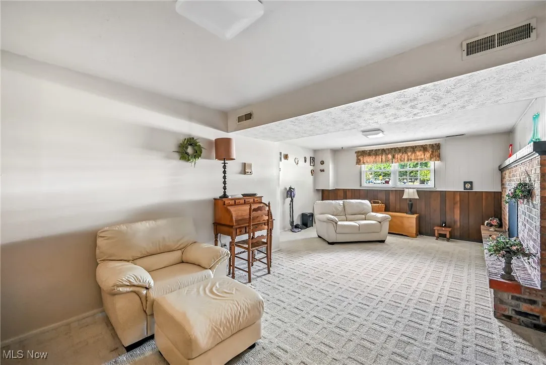 Sitting room with wooden walls, carpet, and a brick fireplace