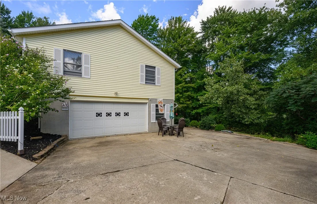 View of home's exterior featuring driveway, a garage, and view of scattered trees