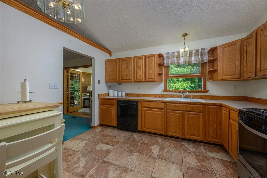 Kitchen featuring a chandelier, open shelves, light countertops, a textured ceiling, and stainless steel gas range oven