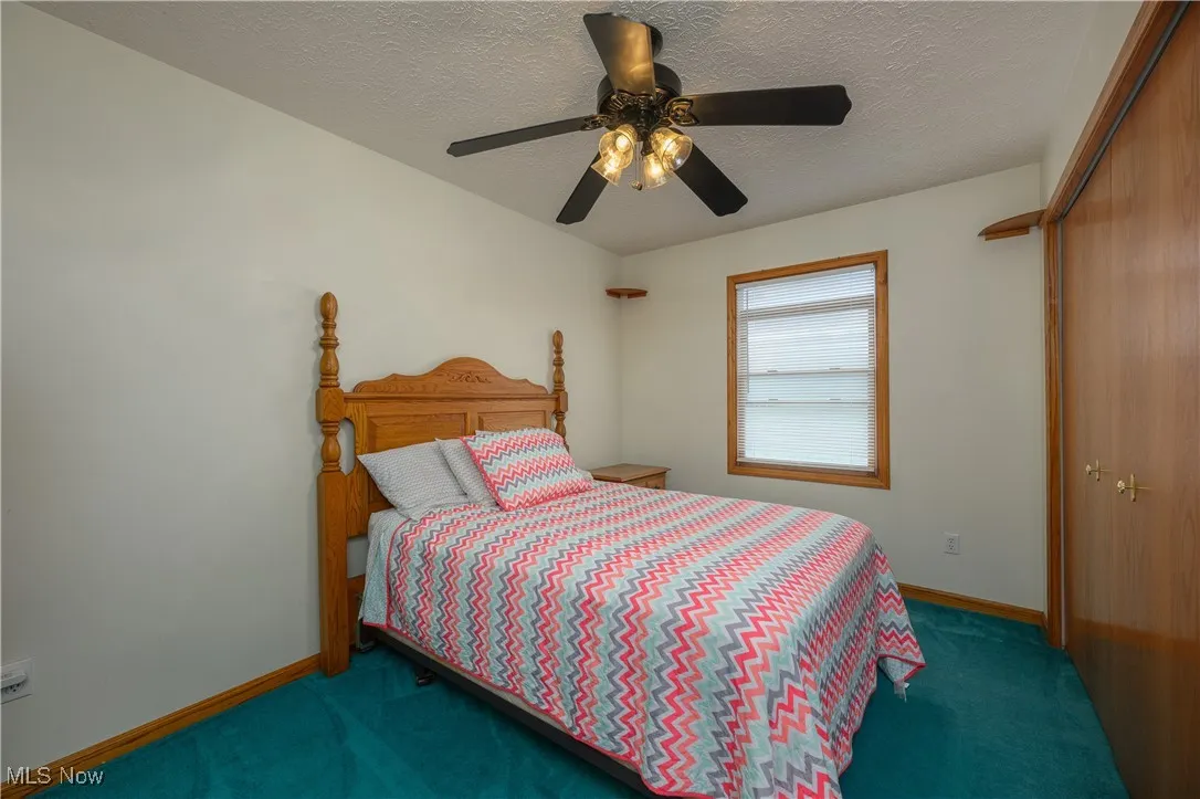 Carpeted bedroom with a textured ceiling, a closet, and ceiling fan