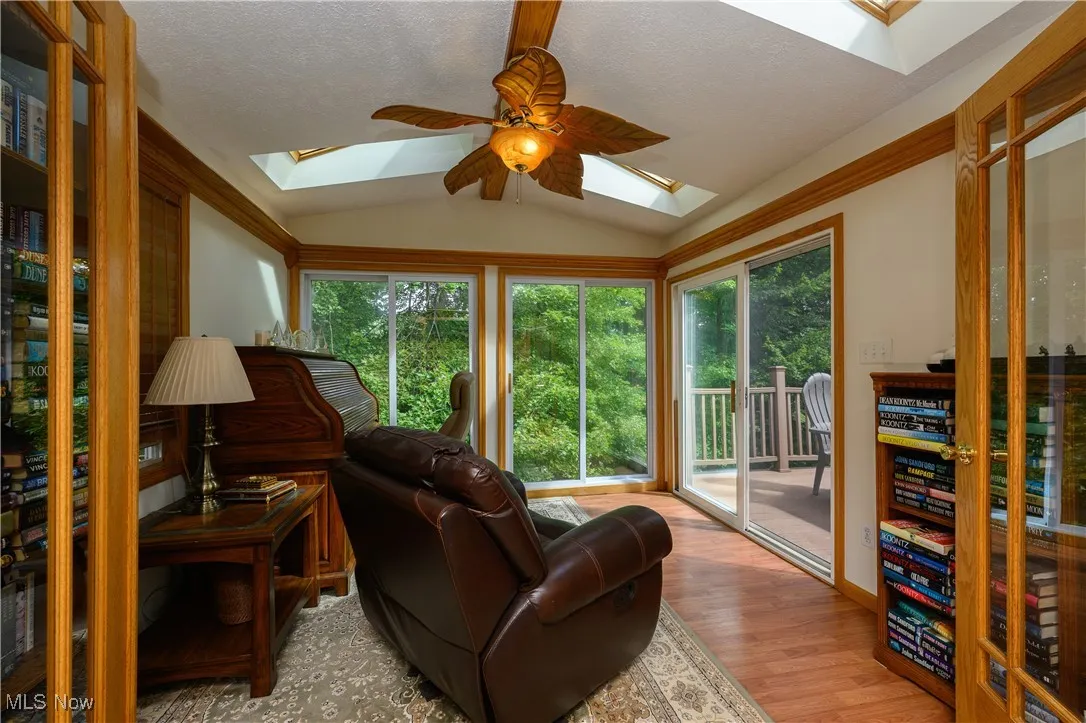 Sunroom with lofted ceiling, wood finished floors, a textured ceiling, and a skylight