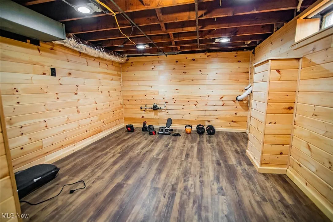 Exercise room featuring wooden walls and dark wood-type flooring